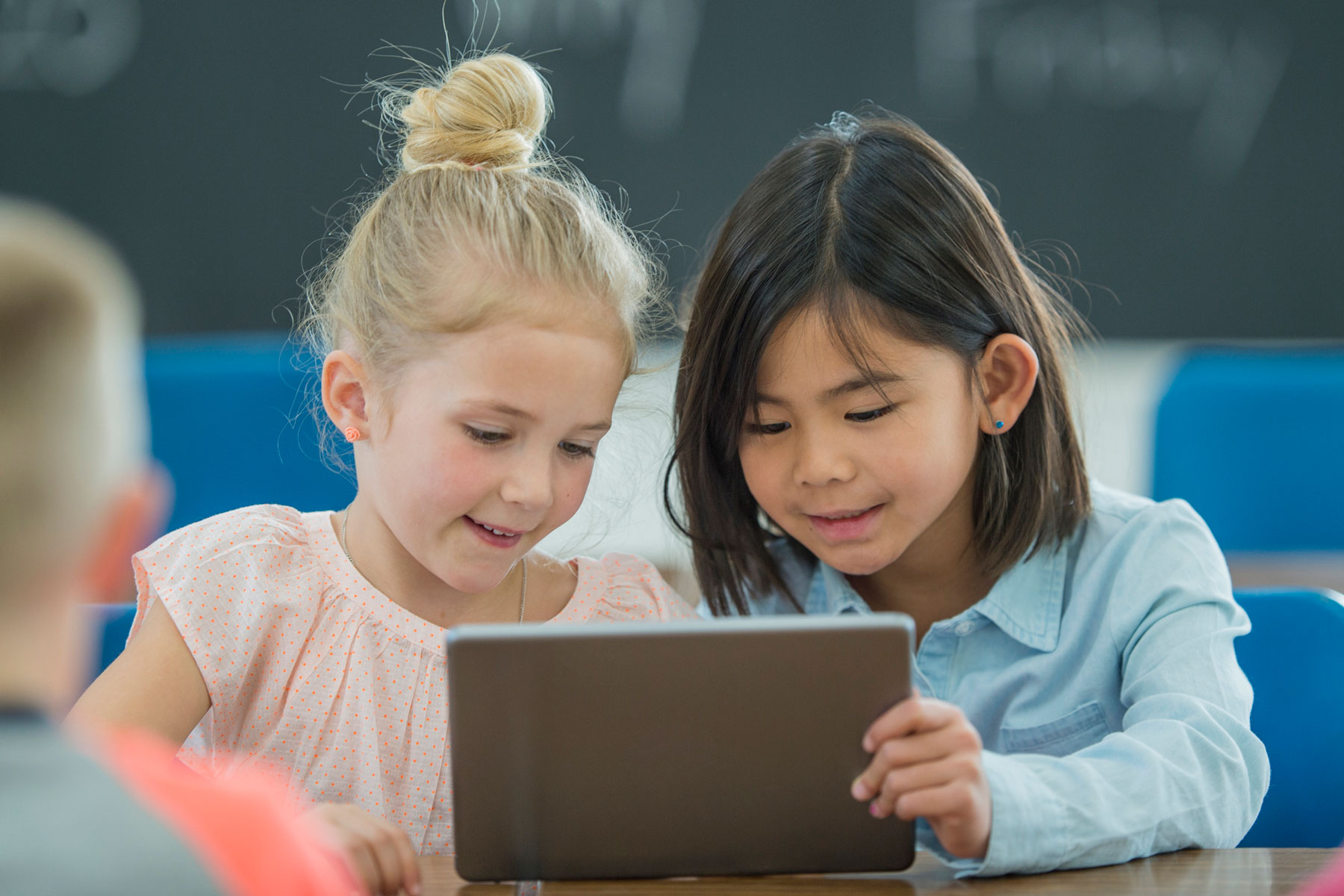 two children working together on tablet device program