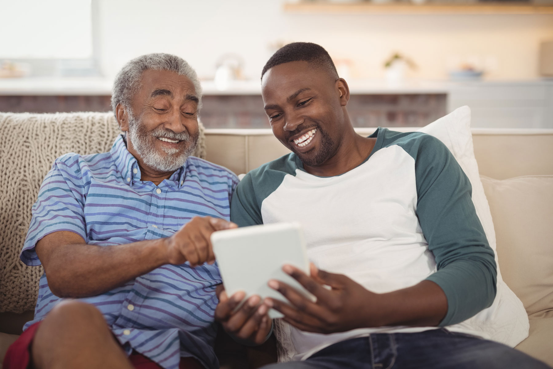 grandfather with son reviewing newsletter on tablet device